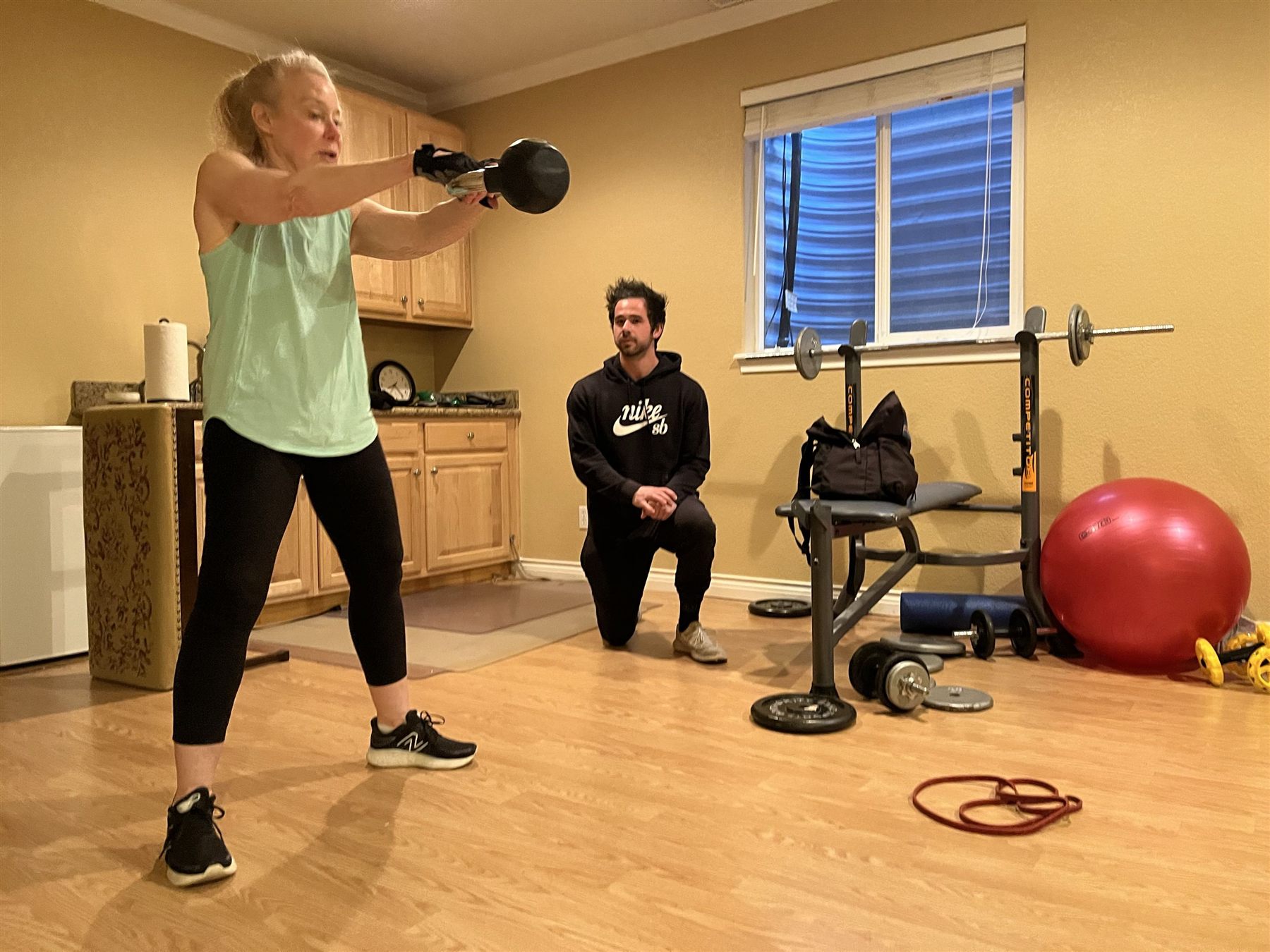 Justin coaching a client through kettlebell swings in her home gym.